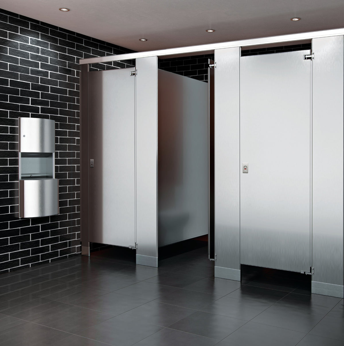 Stainless steel toilet partitions with black tile wall